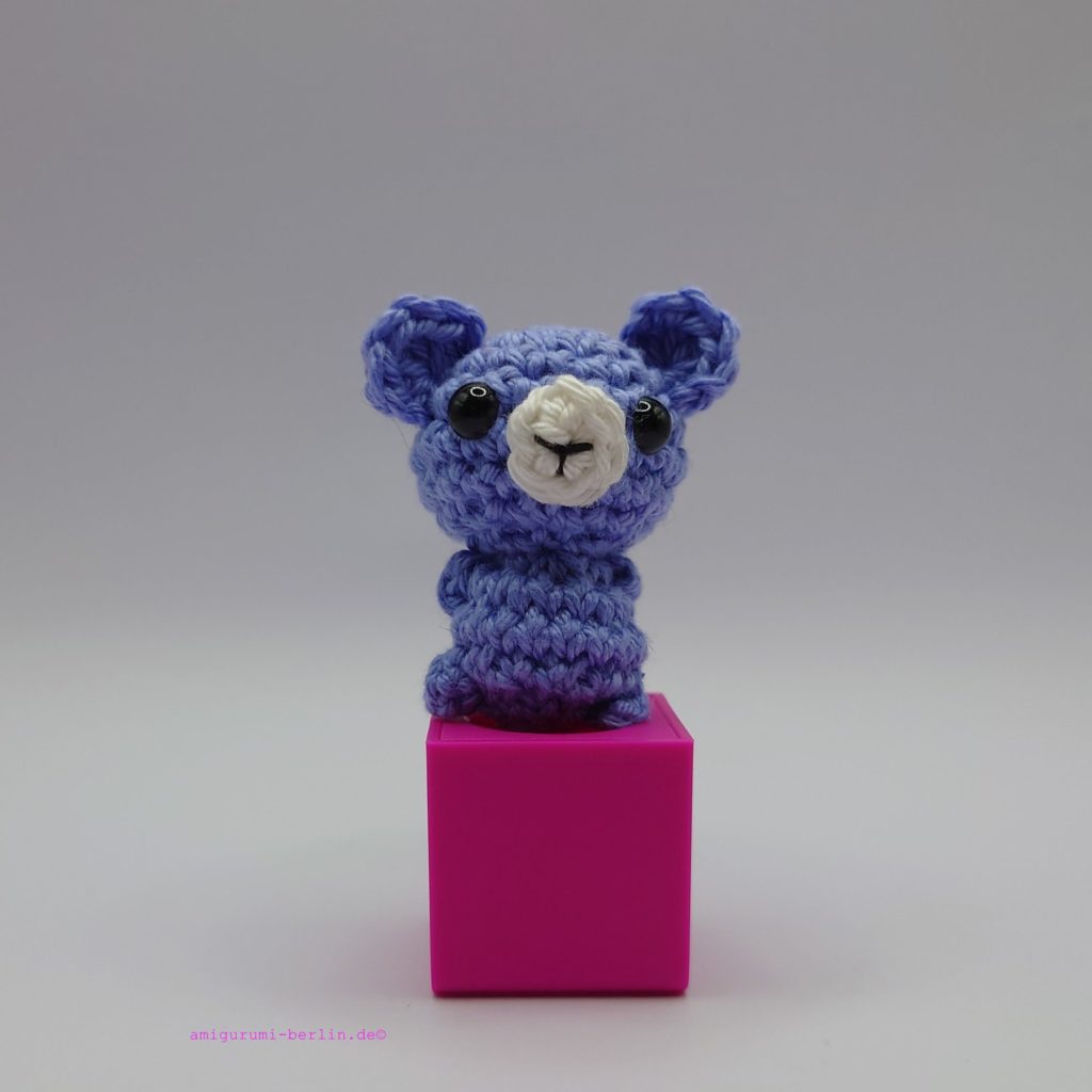 ein wolkefarbener gehäkelter Bär auf einem pinkfarbenen Block - a cloud-coloured crocheted bear on a pink block