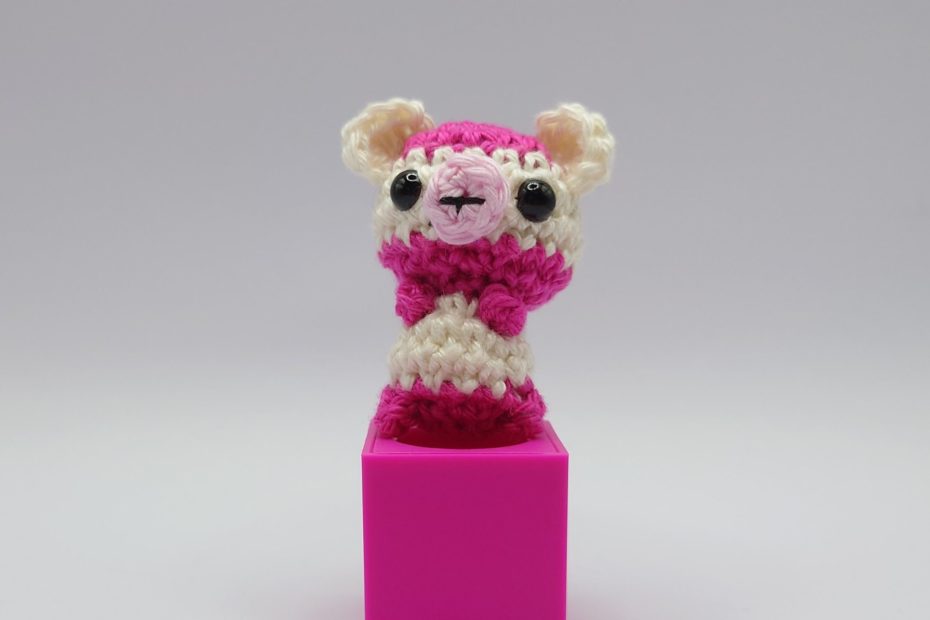 ein weiß-pinkfarbener gehäkelter Bär auf einem pinkfarbenen Block - a white-pink-coloured crocheted bear on a pink block