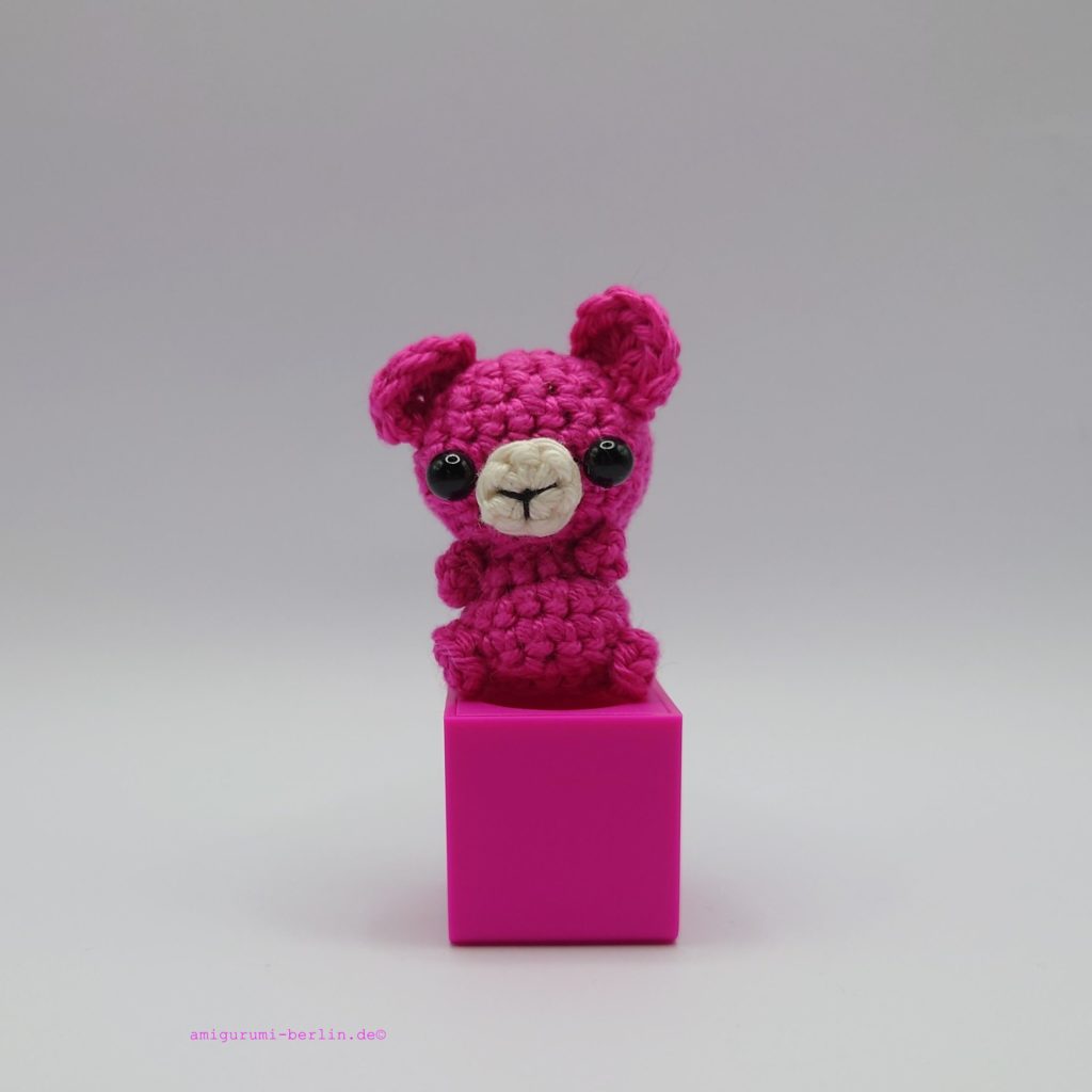 ein pinkfarbener gehäkelter Bär auf einem pinkfarbenen Block - a pink crocheted bear on a pink block