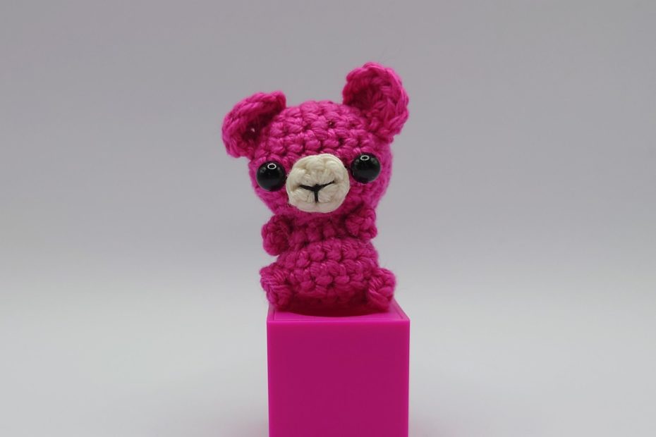 ein pinkfarbener gehäkelter Bär auf einem pinkfarbenen Block - a pink crocheted bear on a pink block